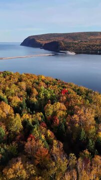 Ingonish Beach along Cabot Trail, Cape Breton, Nova Scotia, Canada. Incredible blue ocean waters with  the autumn fall foliage colors. [Vertical Video]