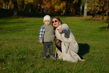 Mother joyfully awaits her young child running towards her in a sunny autumn park. Warm embrace, love, and bonding moment in nature surrounded by vibrant fall colors.