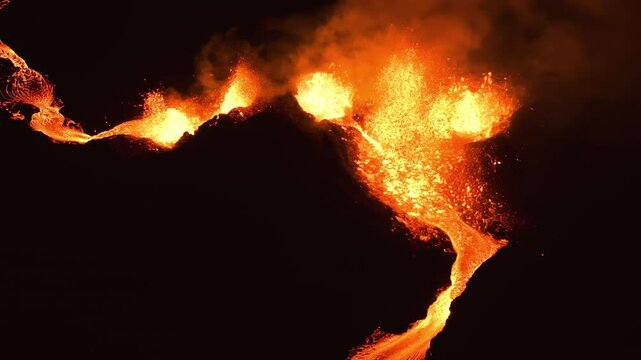 Drone shot of Magma exploding from a fissure at a Volcano crater, night in Iceland