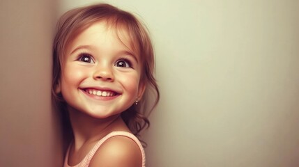 A joyful young girl smiling against a neutral background.