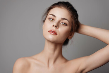 Beautiful young woman with hands on head posing on a gray background