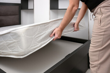 A adult man bought a new mattress for his bedroom.