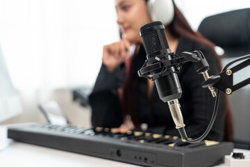 Professional Musician with condenser microphone and tablet for Mixing Mastering music. Music composer woman composing a song with guitar and piano keyboard at digital Recording home studio