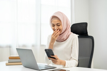 Young asian muslim businesswoman holding smartphone in the office. CEO Businesswoman islamic muslim analyzing statistics financial Meeting Conference Discussion topic Corporate working with laptop