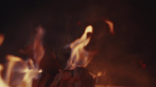 Slow motion Macro shot of wood logs burning in a campfire with sparks and smoke