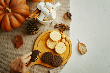 An inviting autumn scene with biscuits, marshmallows, pumpkin, leaves, and seasonal decor, perfect for a cozy gathering