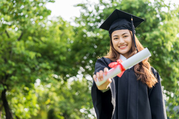 Happy asian woman in graduation costume with cap standing outdoor public park. College degree successful education graduation in university.