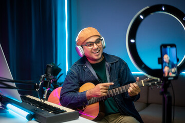 Professional Musician with condenser microphone and tablet for Mixing Mastering music. Music composer male composing a song with guitar and piano keyboard at digital Recording home studio