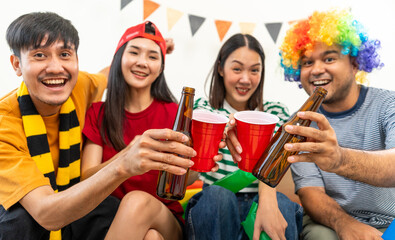 Group of asian friends man and woman watching cheering football match on TV at home. Eating snack and drinking beer. Sport fans people shouting and celebrating sport team victory match.