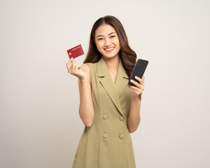 Naklejka premium Portrait beautiful asian women standing pose holding credit card and smartphone to shopping payment. Attractive Happy businesswoman input the serial number of credit card cell phone financial