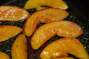 Frying peach slices in butter in a frying pan