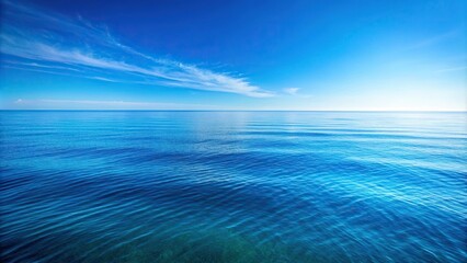 Obraz premium A vast expanse of calm ocean waters reflecting a clear blue sky with only a few wispy clouds scattered across the horizon, shoreline, calm water, natural beauty, sea, beach scenery