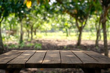 Fototapeta premium Empty rustic wooden table perfect for displaying products with a blurred green orchard in the background