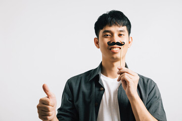 A smiling Asian man is portrayed in a portrait, holding a funny mustache card, exuding joy and...