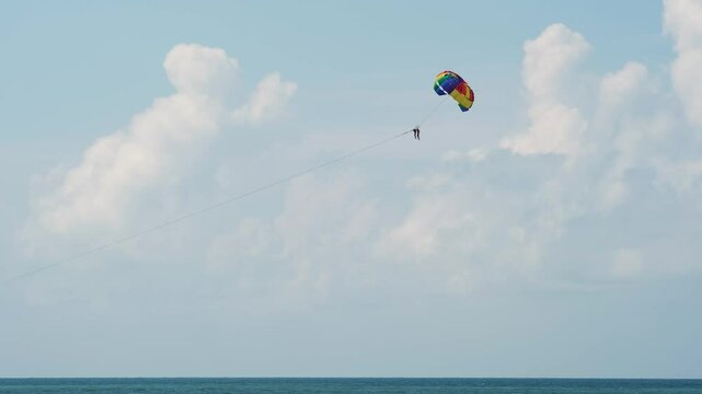 A parachutist glides through the sky above the ocean, capturing the thrill of adventure and sports. This scene embodies the excitement of outdoor activities, perfect for themes of leisure and fun.