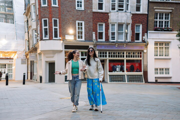Young woman helping her blind friend walking in the city