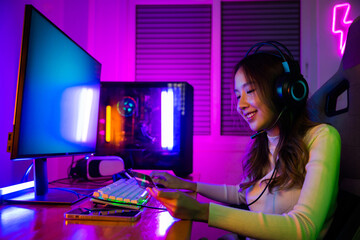Happy young Asian woman gamer wearing headphones she smile holding card account after pay game online, female enjoying using credit card playing gaming with money © sorapop