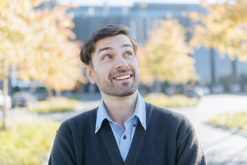 Smiling Male Employee Relaxing Outside, Looking Reflective