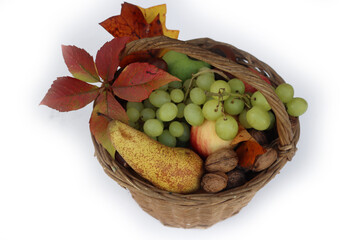 Various fresh autumnal fruits in a wicker basket with orange and yellow leaves. Grapes, apples,...
