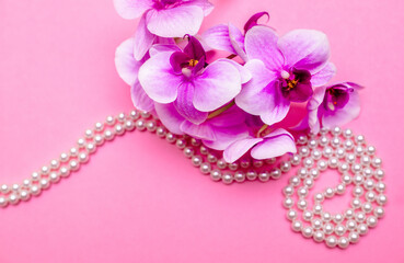 Pearl necklace and Purple orchid on pink background
