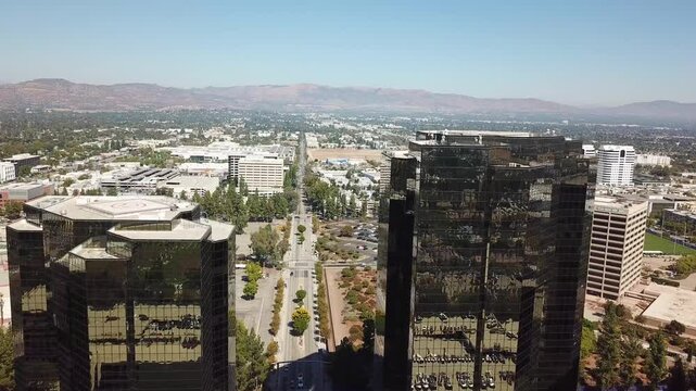 Drone flight between modern mirrored buildings of AIG Capital Service in Woodland Hills. Main street in district of LA, California. Aerial wide shot.