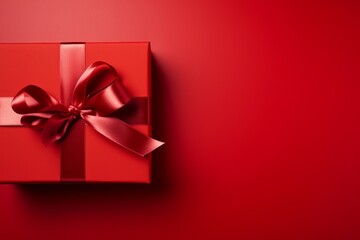 Bright red gift box with a ribbon on a matching red background for festive occasions