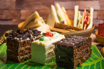 Assorted cakes, Club Sandwich, Toasted Bread, isolated on table closeup side view of Bangladeshi food