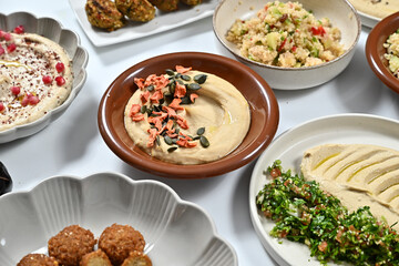 plates filled with various foods on a table that includes hummus, celery