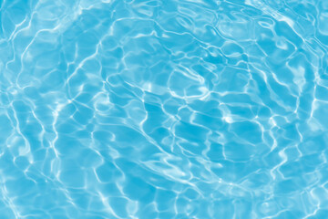 Blue water with ripples on the surface. Defocus blurred transparent blue colored clear calm water surface texture with splashes and bubbles. Water waves with shining pattern texture background.