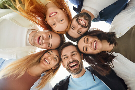 Portrait of a group of happy friends stands in a circle, laughing together in a positive moment. Fun and friendship shared among the diverse group, highlighting joy and connection.