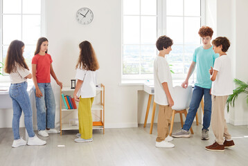School children girls and boys standing in small groups in common modern class room, pre-teens,...