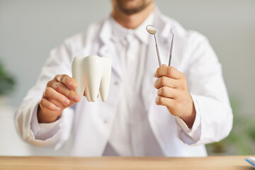 Professional dentist with a tooth and dental examination tools in hands. Male dentist holding a...