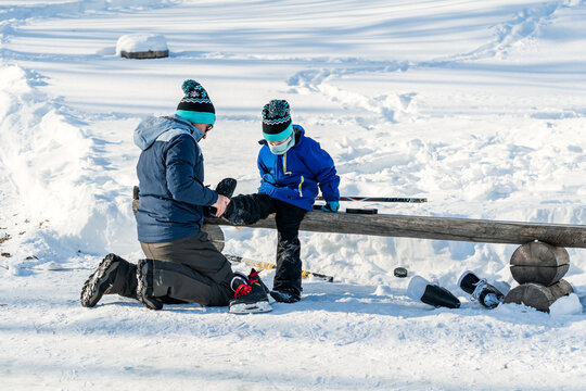 Father helping son prepare for ice hockey