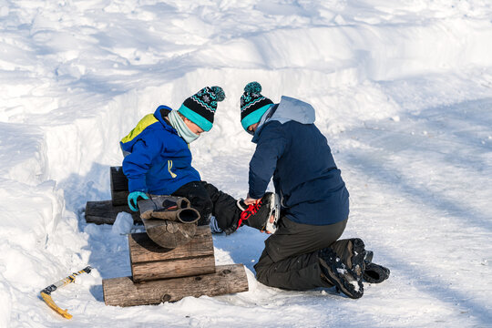 Father helping son put on ice skates