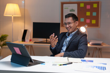 Young professional Asian businessman wearing glasses using laptop, tablet Telephone talk, coordination Review online business information on finance, marketing, startup business ideas. Management.
