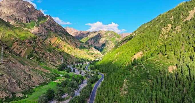 Asphalt highway road and green forest with mountains nature landscape in summer. Beautiful mountain scenery along the Duku Highway in Xinjiang, China.
