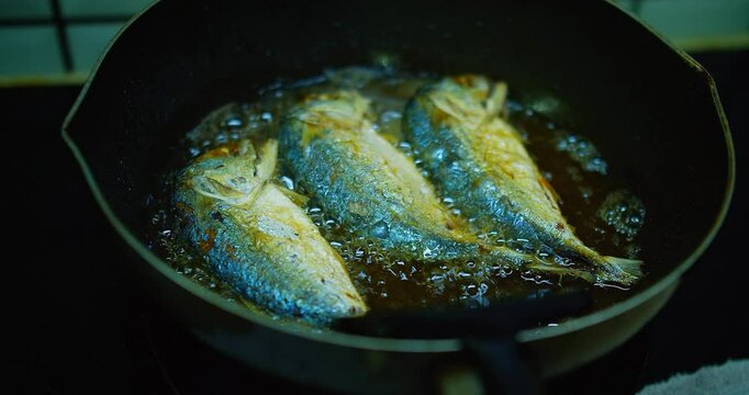 Crispy Fried mackerel Fish frying in a pan on a Stove in a Rustic Kitchen, sizzling in hot oil, showcasing a delicious home-cooked meal.