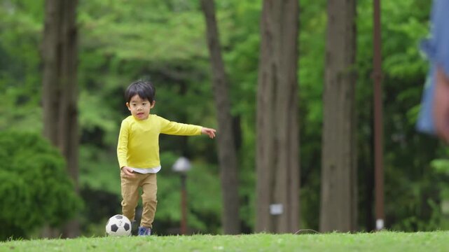 公園で父親とサッカーをする4歳の男の子