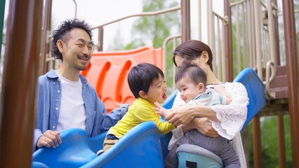 公園の遊具で遊ぶ四人家族