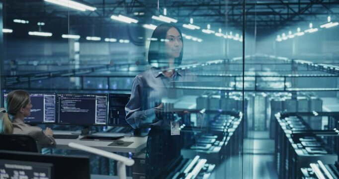 Asian Female Information Technology Engineer Reviews Security Logs on Her Laptop Computer in a High-Tech Data Center, Analyzing Potential Risks to Ensure Network&rsquo;s Safety and Compute Power