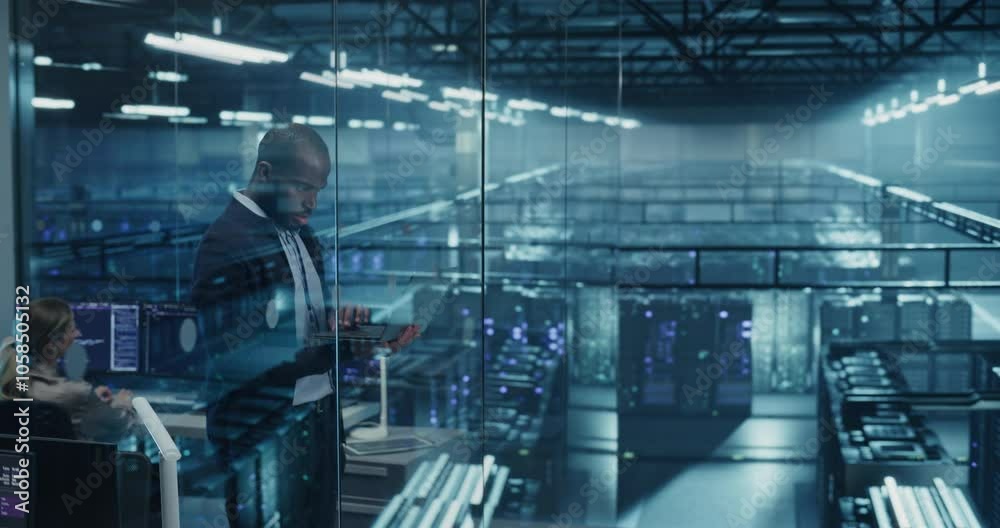 Fototapete Black Male Infrastructure Architect Reviewing Virtualization Strategies on a Laptop Computer, Standing in Office Next to Towering Racks of Servers, Planning to Scale Client Cloud Solutions