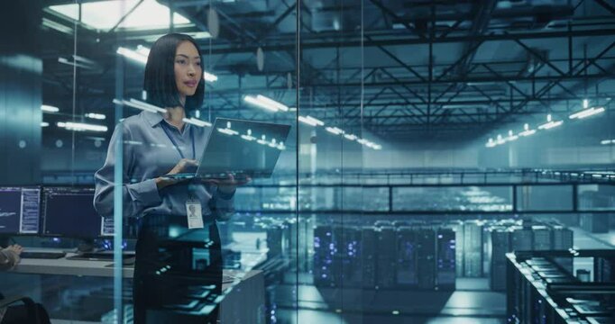 Asian Female DevOps Engineer Monitoring Automation Scripts on Her Laptop Computer, Streamlining Processes of the Data Center IT Infrastructure. Software Specialist Working in Data Protection Field