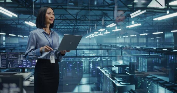 Smiling Asian Female Data Center Specialist Analyzes Server Performance on a Laptop, Optimizing Network Efficiency in a High-tech Environment. Developer Manages Cybersecurity and System Reliability
