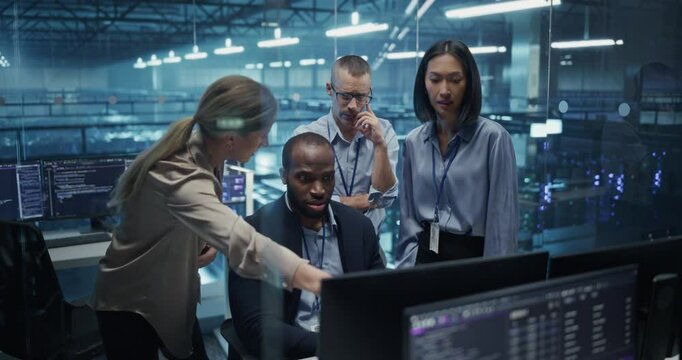 Diverse Team of IT Professionals Gathered Behind a Desk, Looking at Data on Computer Screens, Problem Solving a Data Security Project, Brainstorming Future Upgrades for Cloud Computing System - Powered by Adobe