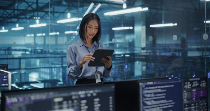 Asian Female Systems Administrator Standing in a Glass Office, Adjusting Configuration Settings on Her Tablet Computer, Operating Cloud Services Servers for Artificial Intelligence Training