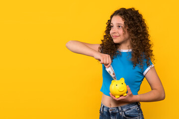 Girl putting money into a piggy bank, symbolizing savings and financial awareness