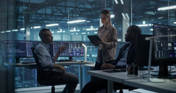 Two Young Male Sitting Down and Female Standing with a Tablet Computer Exchange Ideas in the Data Center Office, Discussing a Project Proposal, AI Development and Solutions