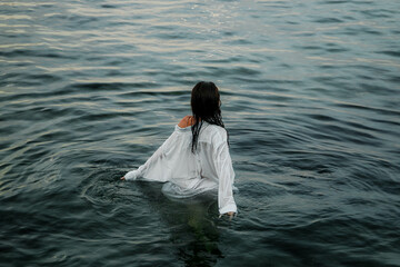 photoshoot of a girl wearing a wet white shirt and underwear on the sea