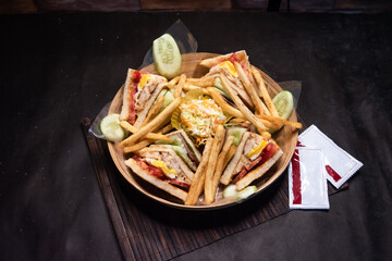 ultimate club sandwich with french fries and sauce served in basket isolated on dark background side view of bangladeshi fast food