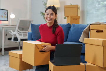 Small business startup idea. SME owner. Female entrepreneur working on packaging boxes. online products Receipt and check orders To prepare to pack boxes for sale to customers.